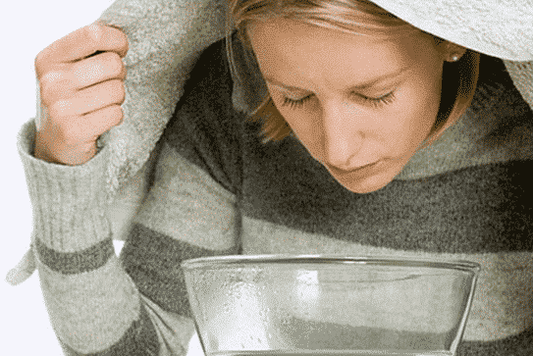 vrouw die haar huid stoomt boven een grote pot water